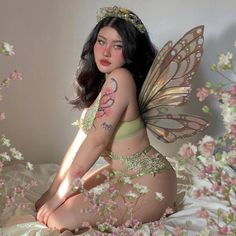 a woman with tattoos on her body sitting on a bed covered in flowers and butterflies