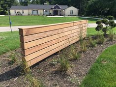 a wooden fence in front of a house with grass and bushes growing on the side