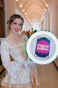 a woman in a white dress holding up a photo booth sign