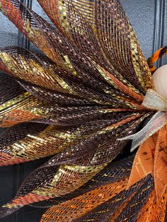 a close up of a wreath with orange and gold ribbons on it's front door