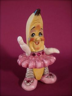 a ceramic figurine of a banana wearing a pink dress