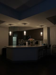 a kitchen with an island in the middle and lights hanging from the ceiling above it