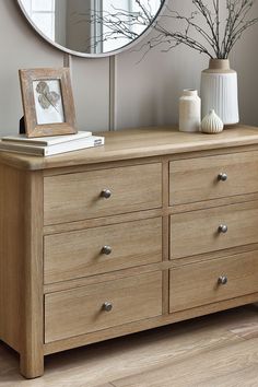 a wooden dresser sitting in front of a round mirror