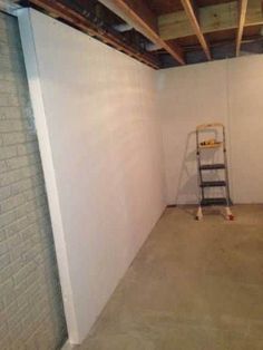 an empty room with a ladder in the corner