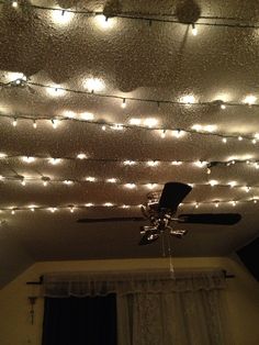 a ceiling with lights and a fan in the middle is lit up by string lights