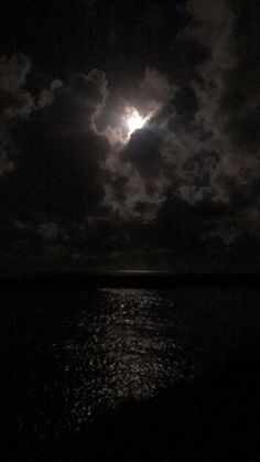 the moon is shining brightly in the dark sky over the ocean with clouds and water