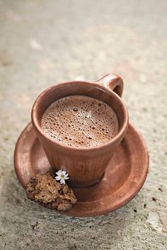 a cup of hot chocolate on a saucer next to a piece of cookies and a cookie