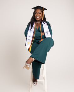 a woman sitting on top of a stool wearing a graduation cap and gown