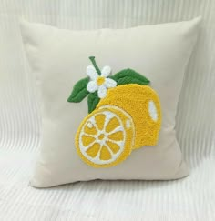 a white pillow with a yellow lemon and flower appliqued on the front