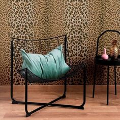 two chairs sitting next to each other in front of a wall with leopard print on it