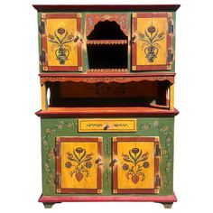 an ornate painted wooden cabinet with two doors and three drawers on the front, one door open