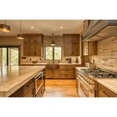 a large kitchen with wooden cabinets and marble counter tops, along with stainless steel appliances