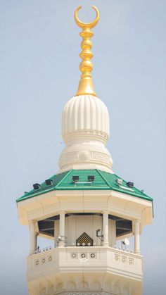 the top of a white building with a gold crescent on it's roof and a sky background