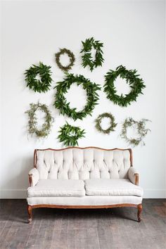 a couch sitting in front of a wall with wreaths hanging on it's side