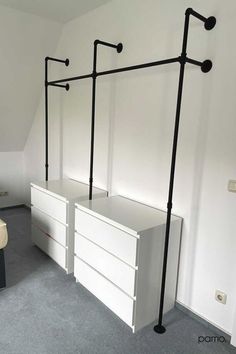 an empty bedroom with two white drawers and black handles