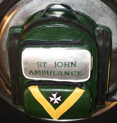 there is a cake made to look like a backpack with the name st john ambulance on it