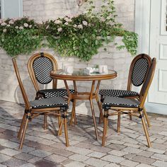 the table and chairs are set outside on the brick patio with flowers in the window box