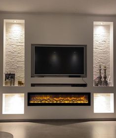 a modern living room with a large television and fireplace in the center, lit by recessed lights