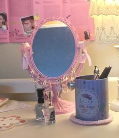 a pink vanity mirror sitting on top of a table next to a cup and pen holder