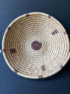 a brown and white woven basket sitting on top of a table next to a black wall