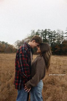 a young man and woman standing in a field