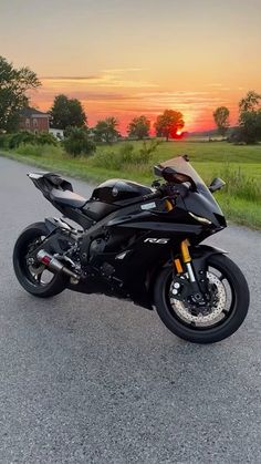 the motorcycle is parked on the side of the road in front of an orange sunset