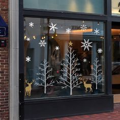 a store window with snowflakes and reindeers in the windows, on a brick sidewalk