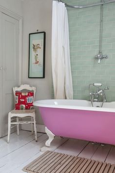 a pink bath tub sitting next to a white chair