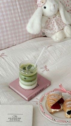 a stuffed rabbit sitting on top of a bed next to a plate with food and drink