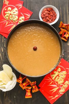 a pan filled with food sitting on top of a table next to red envelopes