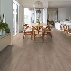 a dining room table and chairs in front of an open floor plan with large windows