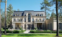 a large house in the middle of some trees and grass with bushes on each side