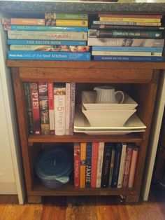 a bookshelf filled with lots of books next to a bowl and other items