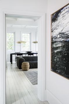 a painting hangs on the wall next to a couch in a room with white walls