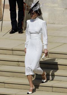 a woman in a white dress and hat walking down some steps