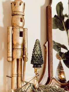 a wooden nutcracker next to a mirror with a christmas tree on it and a small toy soldier