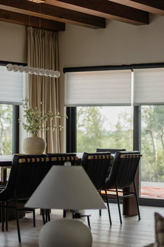 the dining room table is surrounded by black chairs and white vase with a plant in it