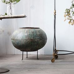 a large metal pot sitting on top of a wooden floor next to a planter