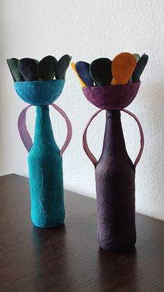 two vases with flowers in them sitting on a table next to each other,