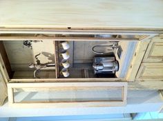 an open cabinet with tea kettles and cups on the top shelf in a kitchen