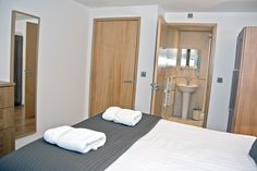 a bed with two white towels on top of it next to a dresser and mirror