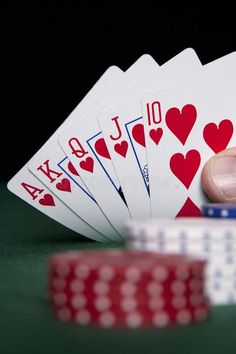 playing cards and poker chips on a table with one hand about to strike the card