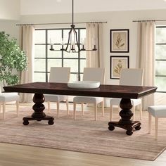 a dining room table with white chairs and a chandelier hanging from the ceiling