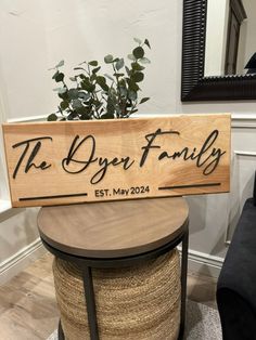 a wooden sign that says the dyer family on it next to a table with a potted plant