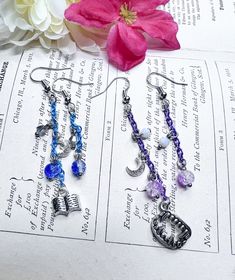 I wanted to do some beautiful earrings for these two. So I came up with these designs. Vanitas is a blue chain with a book and a moon charm with some beads in blue and silver. Noe has his vampire teeth he is purple with shades of purple for his beads and a small moon. Choose between Vanitas and Noe. Want a character we don't have? We do customs. due to the handmade nature of the product there could be some variations in beads but they will be as close to the photo as possible. Vampire Teeth, Asymmetrical Earrings, Moon Charm, Shades Of Purple, Blue And Silver, Beautiful Earrings, Tassel Necklace, Handmade Natural, Jewelry Earrings Dangle