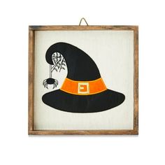 a black and orange witch's hat hanging on a white wall with a wooden frame