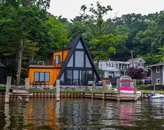 a house on the water next to some houses with boats parked in front of it