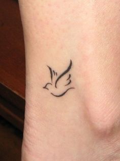 a small tattoo on the ankle of a woman with a bird flying above her foot