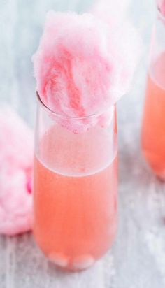 two glasses filled with pink liquid and cotton floss