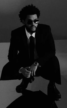 a man in a suit and sunglasses sitting down